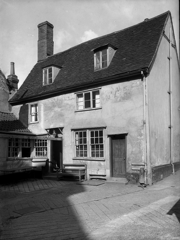 A photo of an old building that looks like a house with a small courtyard in front.